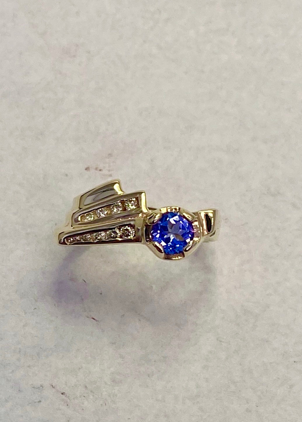 Round-Cut Yellow Gold Tanzanite ring accented with round full-cut diamonds.
